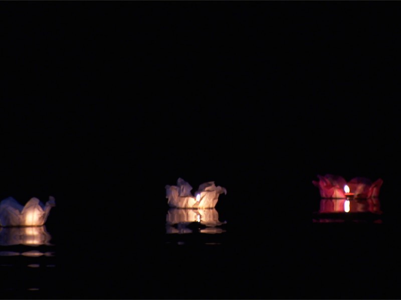 Le lanterne galleggianti luminosi di carta di riso in colori e misure diverse sul fiume canale