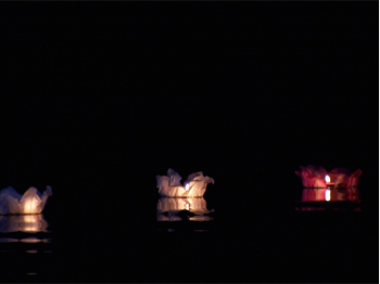 Le lanterne galleggianti luminosi di carta di riso in colori e misure diverse sul fiume canale